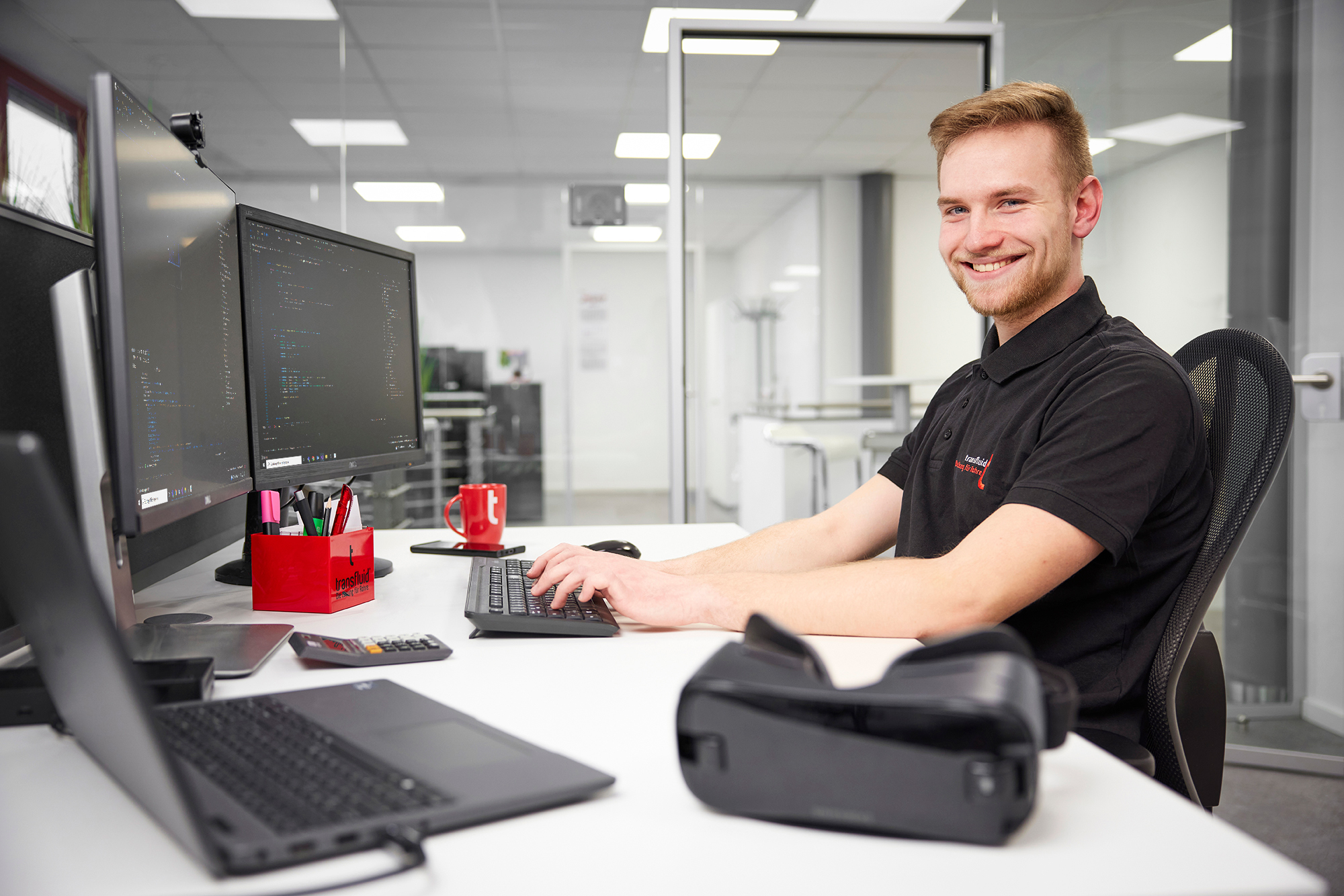 Fachinformatiker arbeitet an Softwarecode im Büro mit mehreren Monitoren.