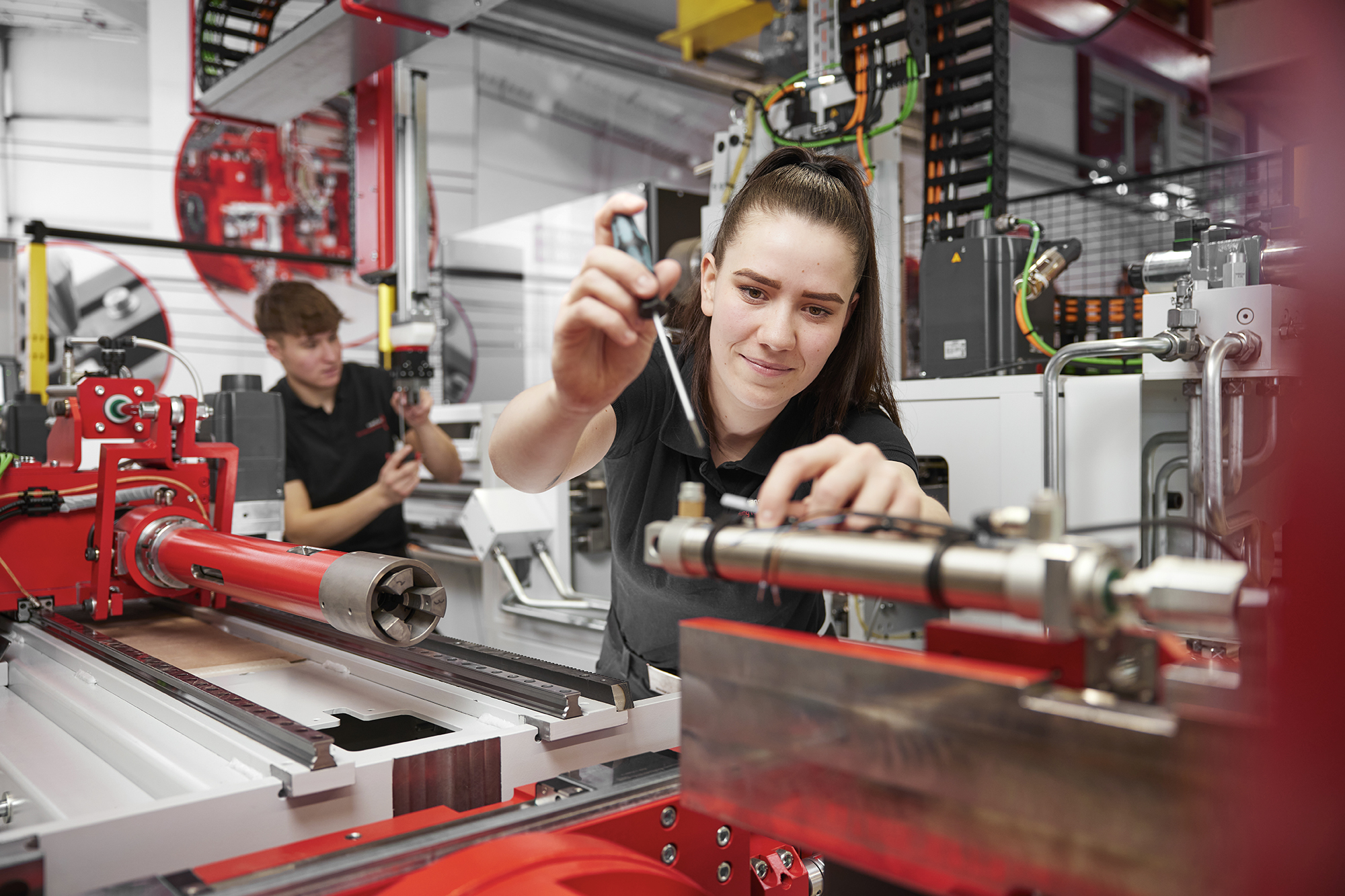 Auszubildende Elektronikerin arbeitet an automatisierter Industrieanlage bei transfluid.