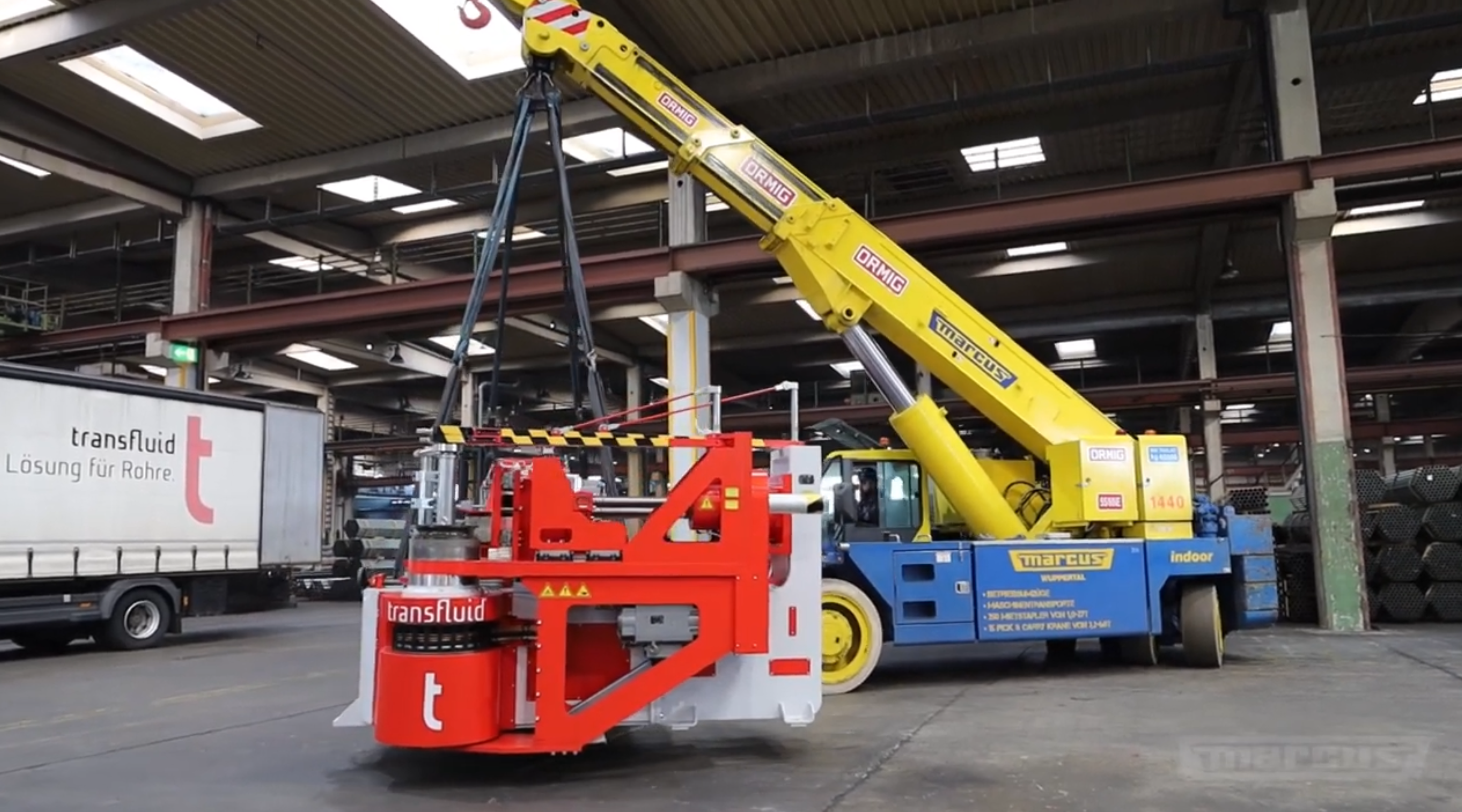 Verladung einer transfluid Rohrbiegemaschine mit Kran in Produktionshalle.