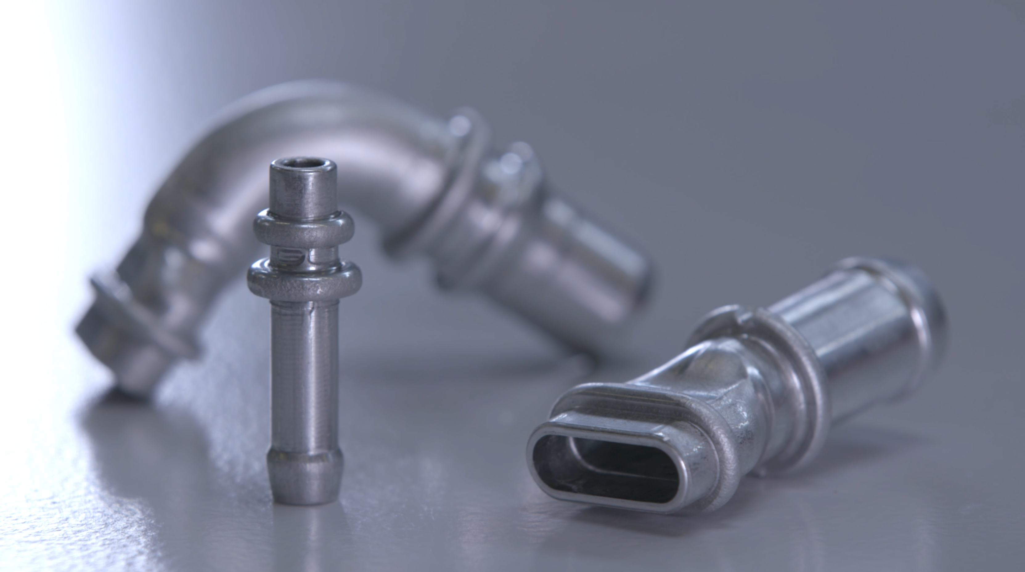 Kurze Metall-Rohranschlüsse und Fittings für Automotive-Fluidtechnik auf Arbeitsfläche.