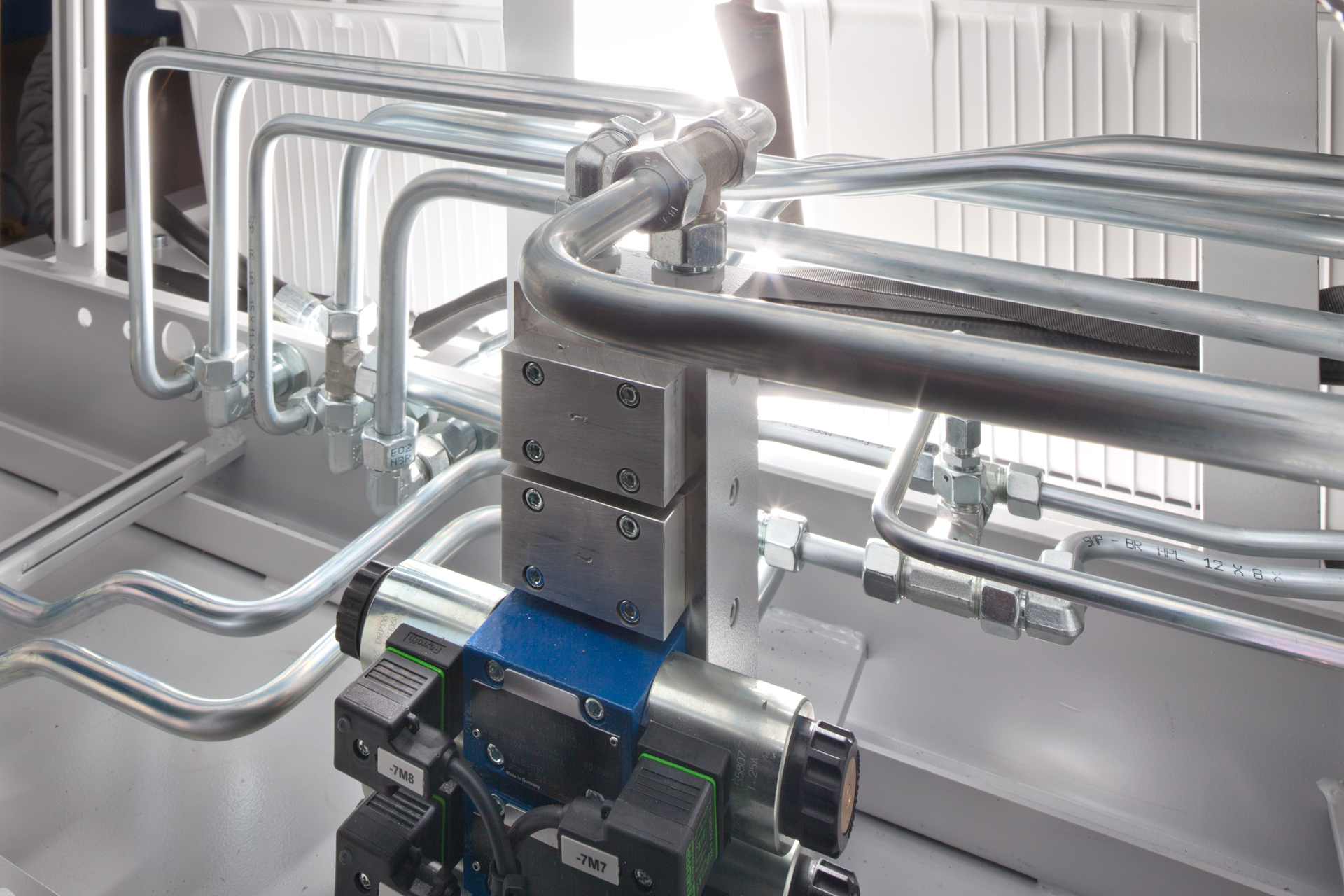 Hydraulisches Rohrleitungssystem mit Ventilblock und Metallrohren.
