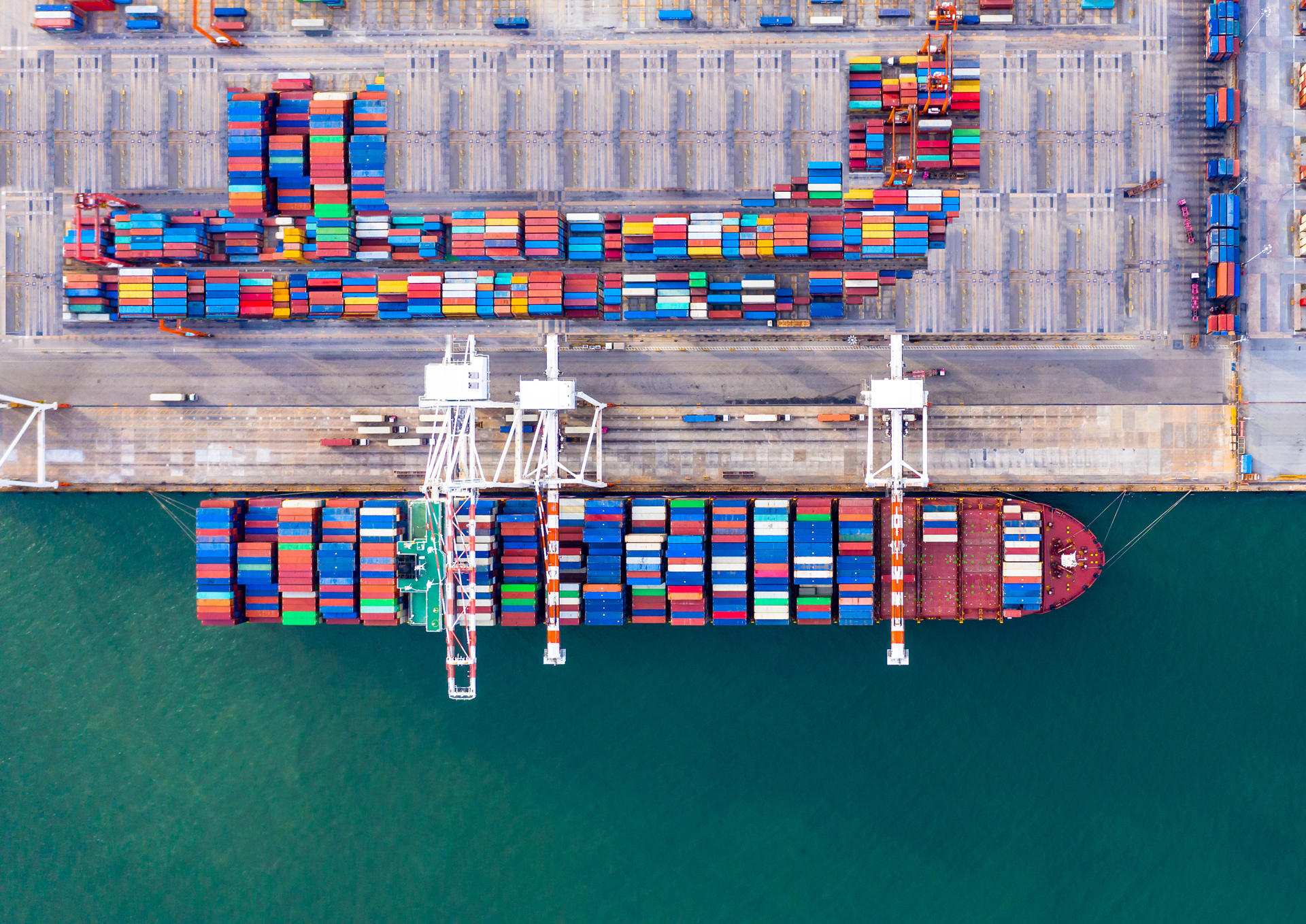 Containerhafen mit Frachtschiff und Verladekranen für maritime Logistik.