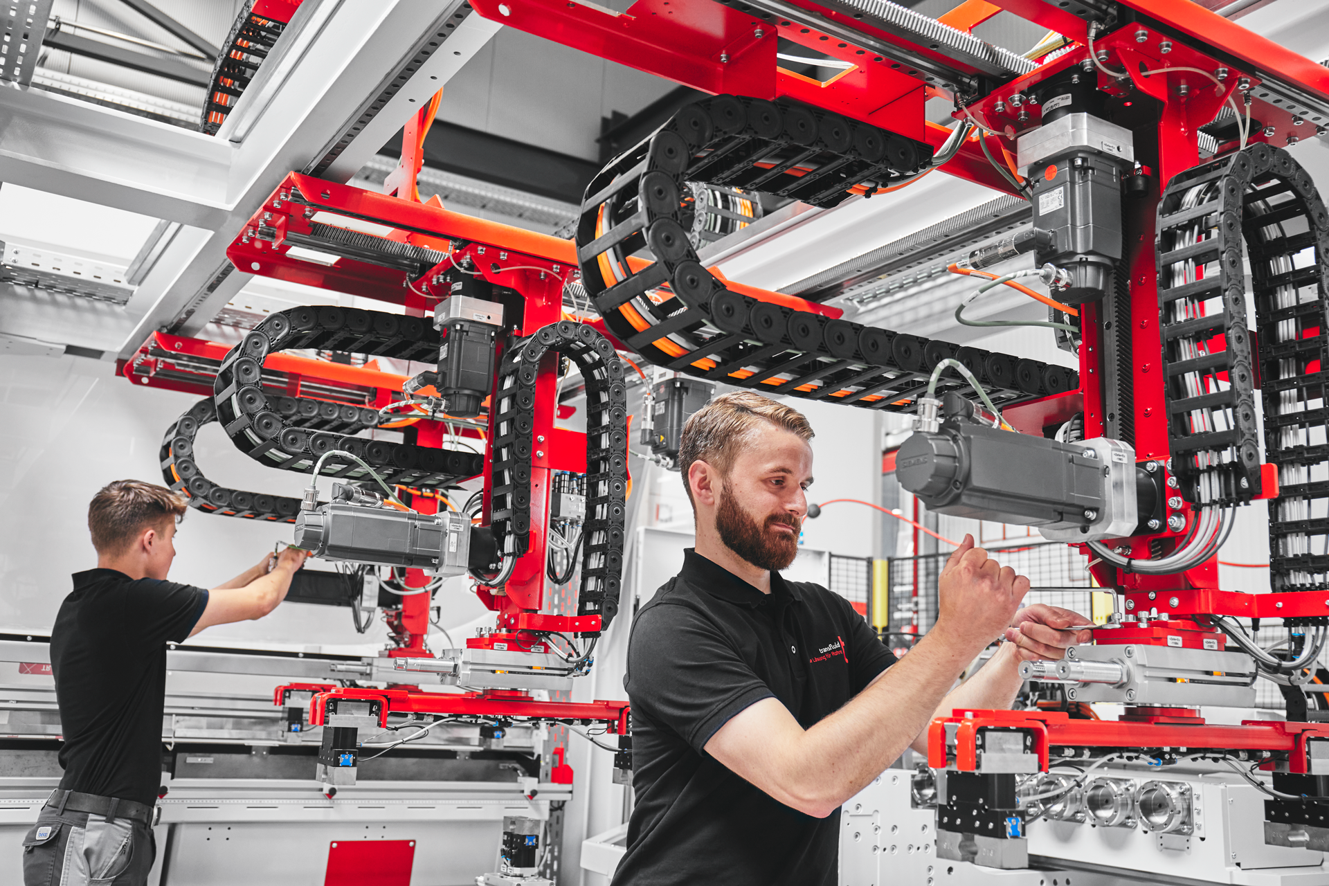 Techniker arbeiten an automatisierter Fertigungsanlage mit Robotiksystem.