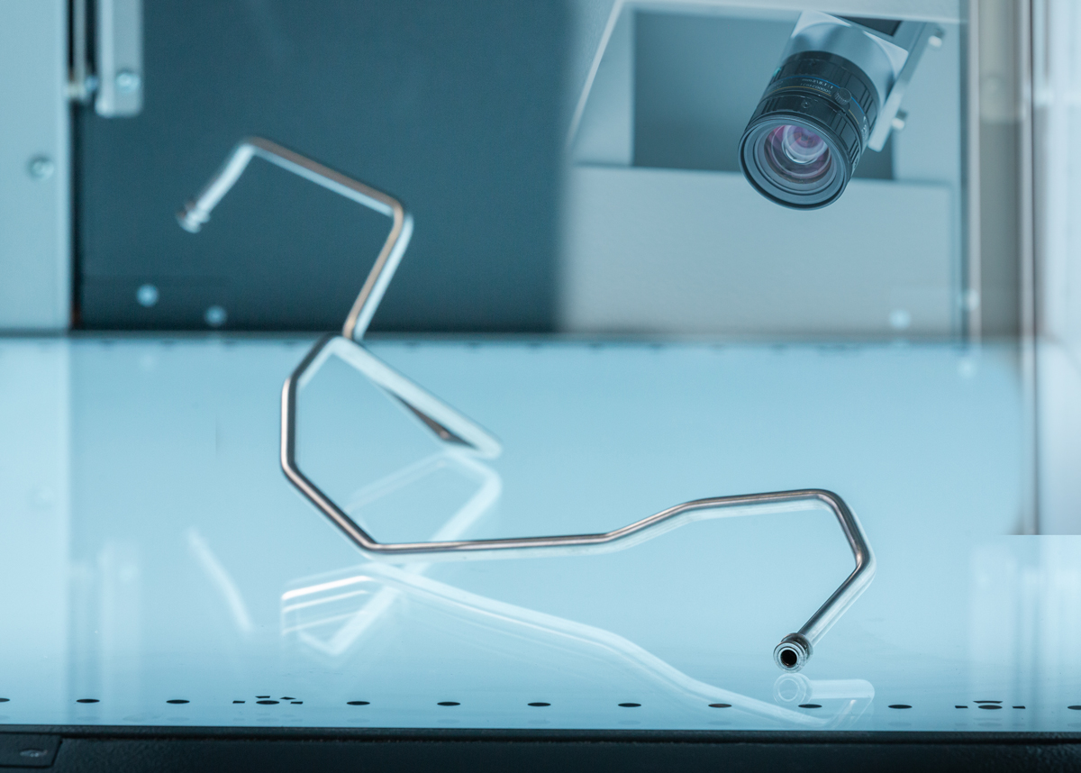 Gebogenes Metallrohr wird mit optischem Messsystem und Kamera vermessen.
