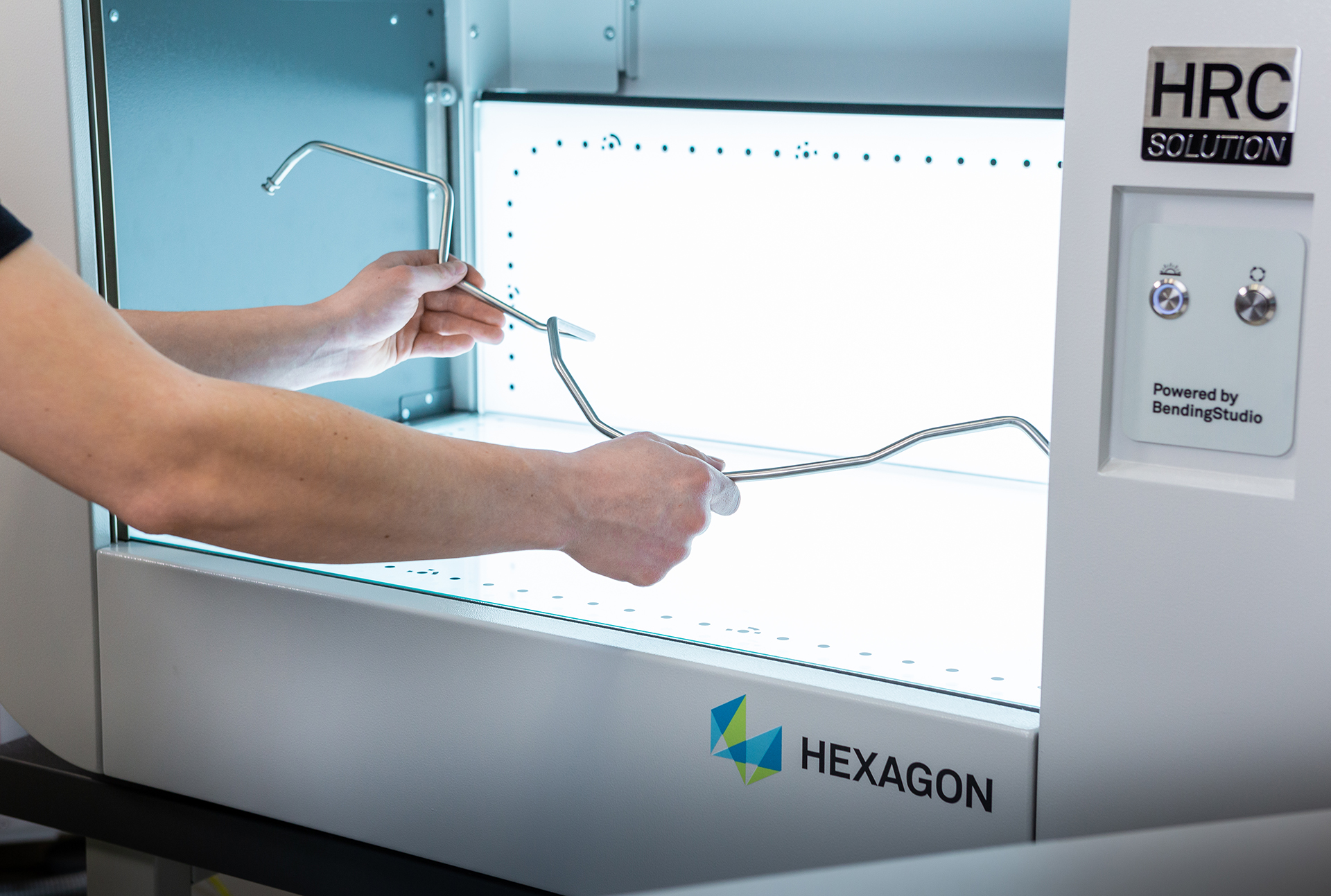 Bediener prüft gebogenes Metallrohr in optischem Messsystem zur Qualitätskontrolle.