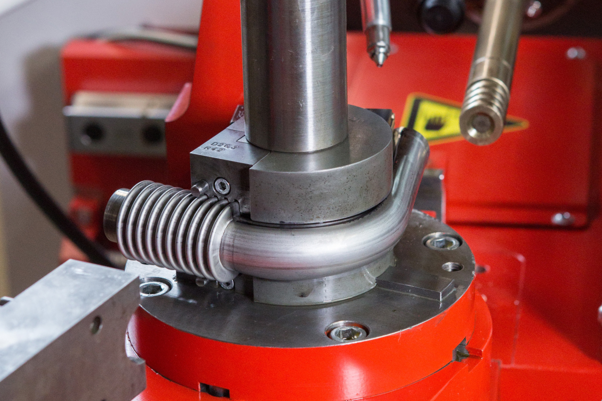 Biegewerkzeug einer transfluid CNC-Rohrbiegemaschine beim Formen eines Metallrohres.