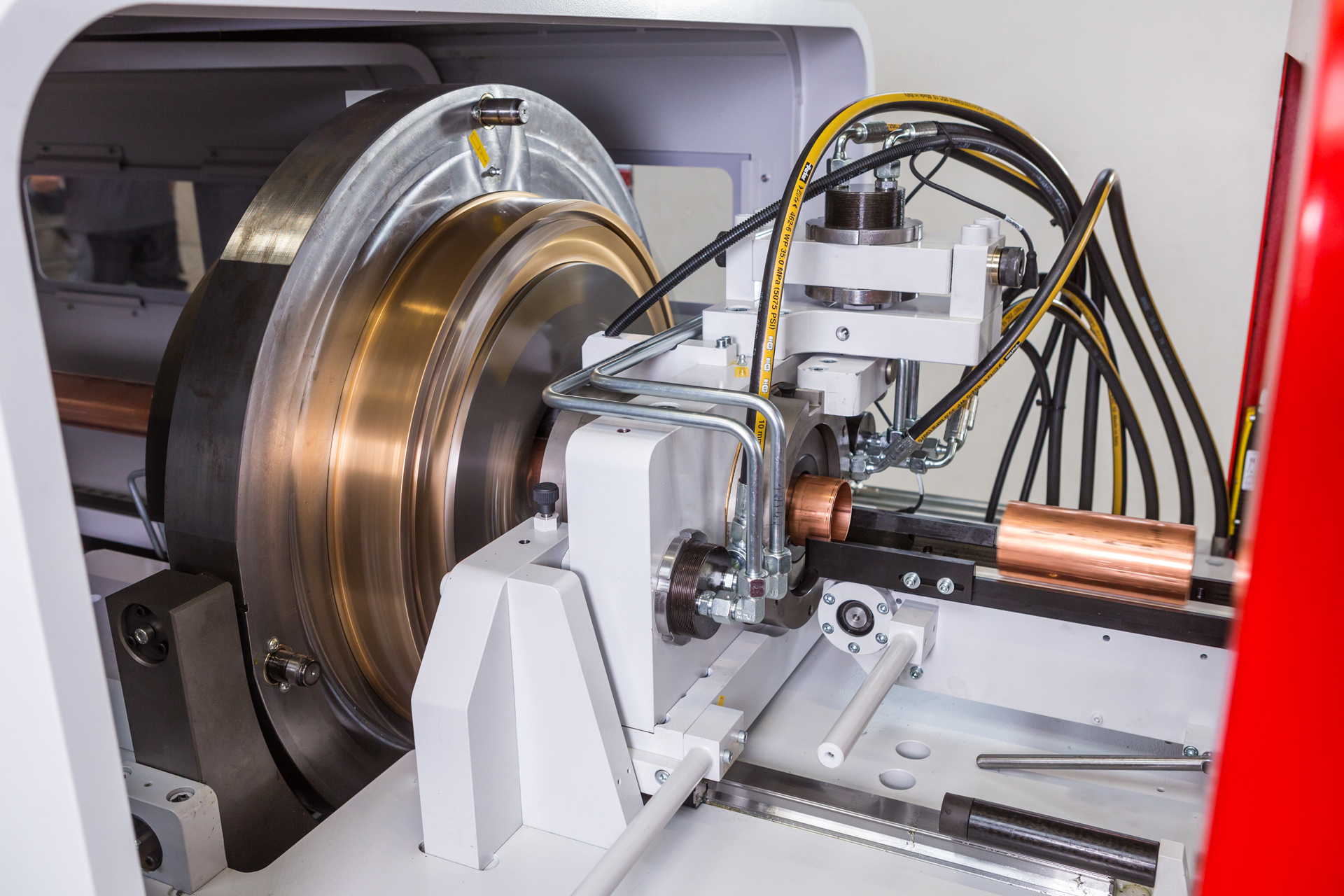 Innenansicht einer orbitalen Rohrtrennmaschine mit rotierendem Schneidrad und automatischer Zuführung eines Kupferrohrs.